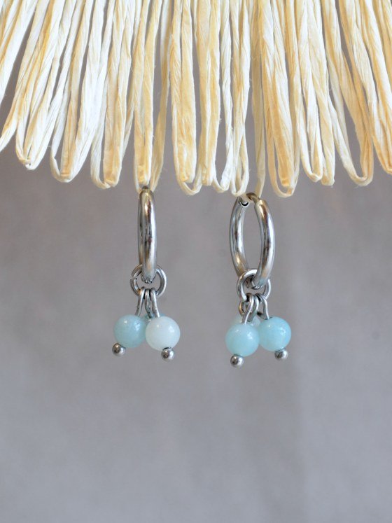 Aretes Belai Amazonita Trio, argollas de acero con racimo de tres cuentas redondas de amazonita celeste, apoyados sobre fibra de rafia y lino