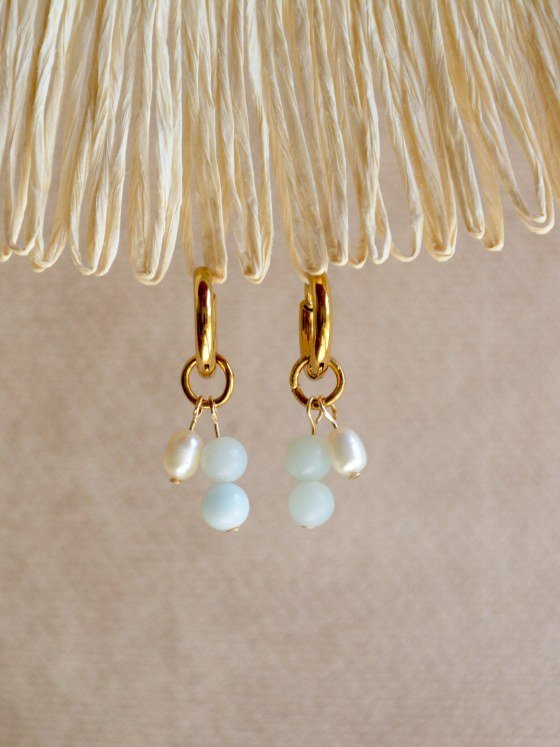 Aretes Belai Amazonita y Perla, argollas de acero con racimo de tres cuentas en abanico: amazonita celeste, perla blanca y amazonita celeste, apoyados sobre fibra de rafia y lino
