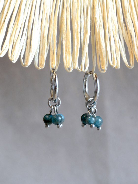Aretes Belai Apatita Trio, argollas de acero con racimo de tres cuentas redondas de apatita azul, apoyados sobre fibra de rafia y lino